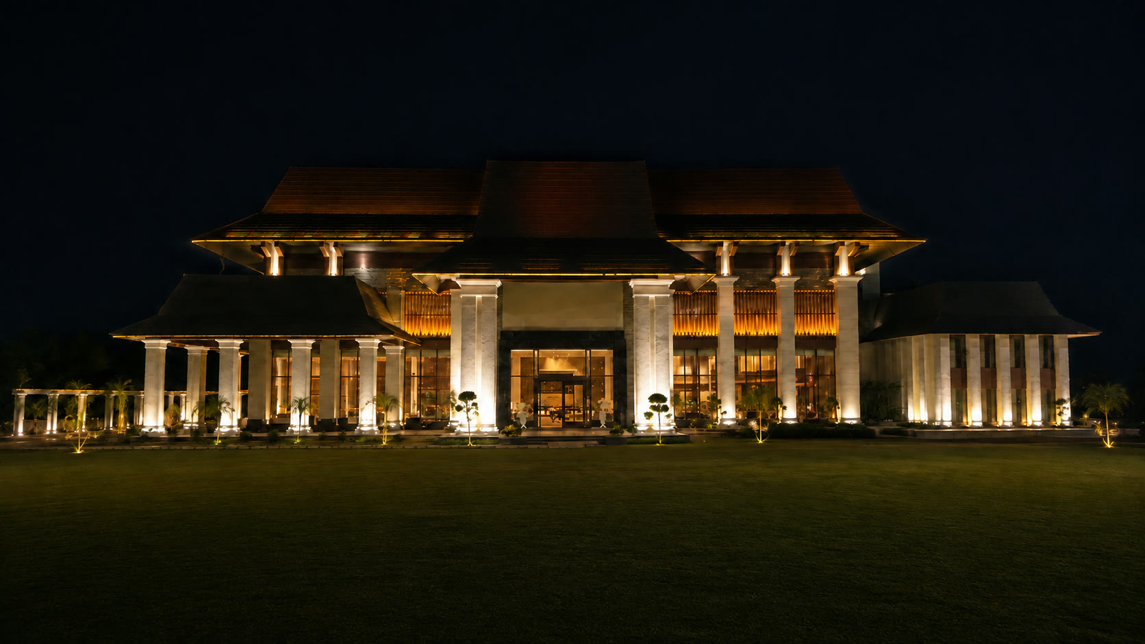 Majestic Grand lit at night, seen across the lawn, a couple walking towards the entrance