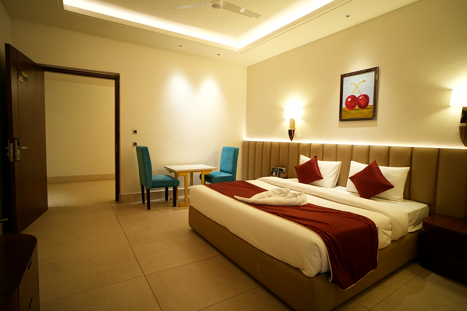 A room with a red-runner bed, padded wall and a table for two